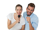 Portrait of a cheerful couple singing into microphones