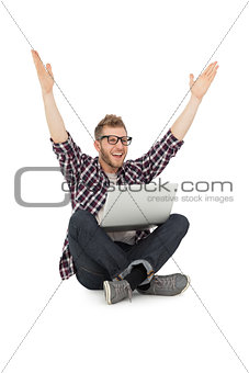 Cheerful young man with laptop raising hands