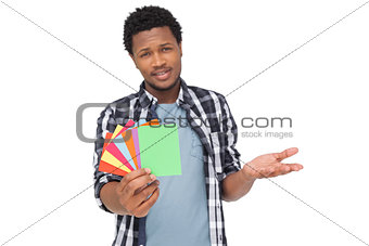 Portrait of a confused man holding colorful papers