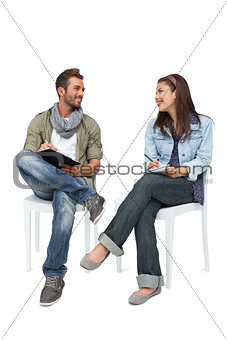 Cool young couple writing in notepads