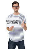 Man holding a donation welcome note while gesturing thumbs up