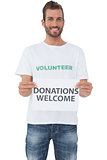 Male volunteer holding 'donations welcome' paper