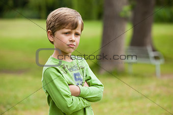 Serious boy standing with arms crossed at park