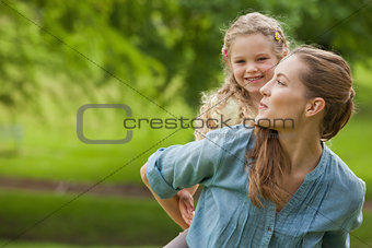 Portrait of woman carrying girl at park