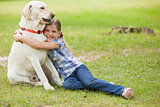 Young girl hugging pet dog at park
