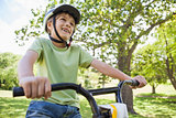 Smiling young boy riding bicycle at park