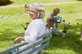 Woman on bench while man watering plant at park
