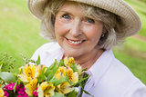 Close-up of smiling mature woman holding flowers at park