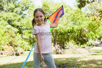 Happy young girl holding kite at park