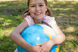 Cute young girl holding globe at park