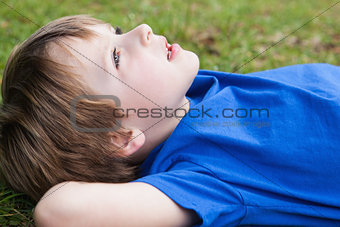Relaxed young boy lying at park