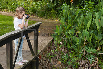 Side view of a girl looking through binoculars at park