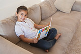 Side view portrait of a girl reading storybook on sofa