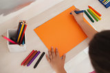 High angle of a girl drawing on orange paper at home