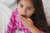 Close-up of a young girl yawning in bed