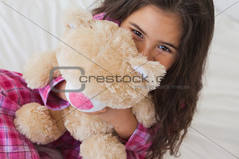 Smiling girl with stuffed toy sitting on bed