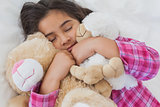 Girl sleeping with stuffed toys in bed