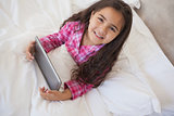 Young girl using digital tablet in bed