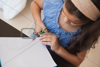 High angle close-up of a girl cutting chart paper