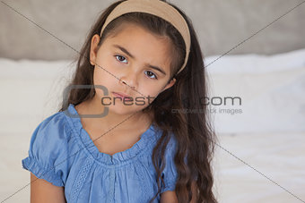 Close-up portrait of a sad young girl on bed