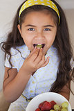 Close-up portrait of a smiling girl eating fruits