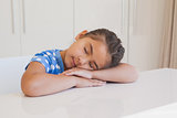 Cute young girl resting head on table