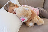 Girl sleeping on sofa with stuffed toy