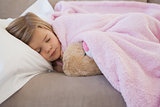 Close-up of a girl sleeping on sofa with stuffed toy