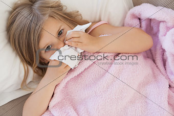 Girl suffering from cold as she lies in bed