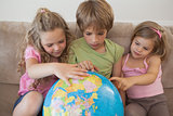 Three kids with globe sitting in living room