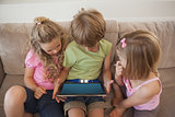 Three kids using digital tablet in living room