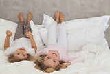 Portrait of two smiling kids lying in bed