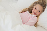 Smiling young girl resting in bed
