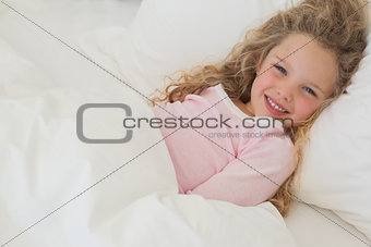 Smiling young girl resting in bed