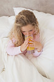 High angle view of girl drinking orange juice in bed