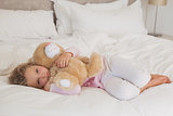 Young girl with stuffed toy resting in bed