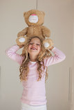Portrait of happy girl holding stuffed toy over head
