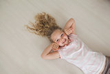 High angle portrait of a smiling girl lying on floor