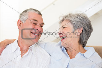 Retired couple sitting on couch smiling at each other