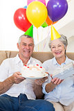 Senior couple sitting on couch celebrating a birthday