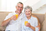 Senior couple sitting on couch drinking orange juice