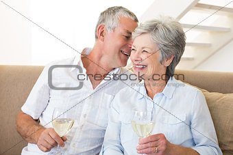 Senior couple sitting on couch drinking white wine
