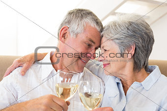 Senior couple sitting on couch having white wine