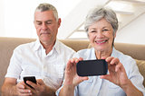 Senior couple sitting on couch using their smartphones
