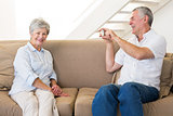 Retired man taking photo of his partner on the couch