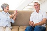 Retired woman taking photo of her partner on the couch