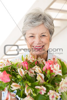 Retired woman holding bouquet of flowers smiling at camera