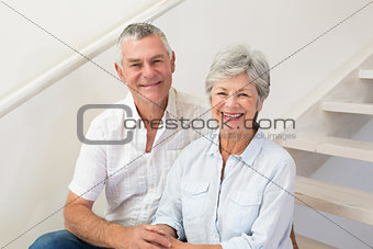 Senior couple sitting on stairs smiling at camera