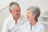 Senior couple sitting on stairs smiling at each other