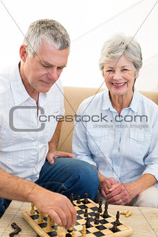 Senior couple sitting on sofa playing chess